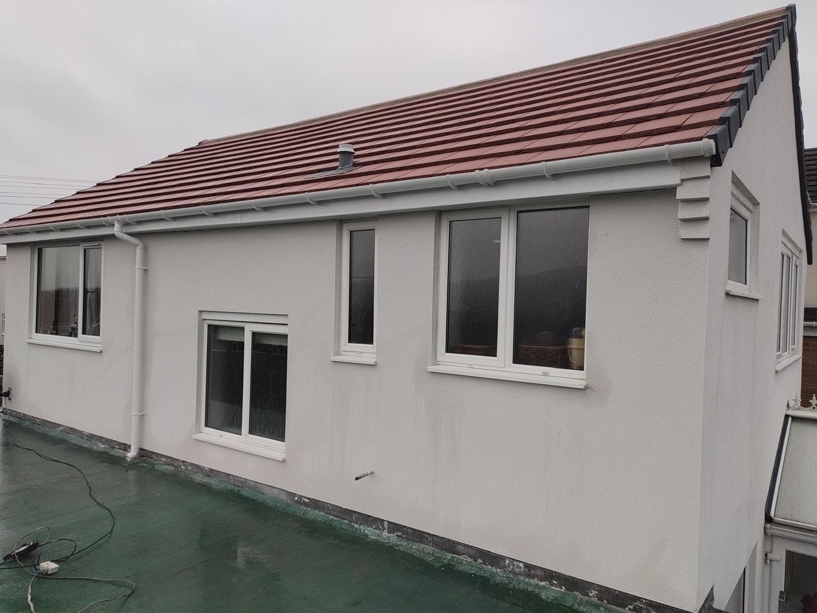 Terracotta pitched roof white render flat roof